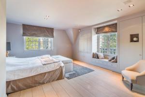 ein Schlafzimmer mit einem Bett und einem Stuhl sowie zwei Fenstern in der Unterkunft Luxe duplex villa8p in cottagestijl met wellness in Knokke-Heist