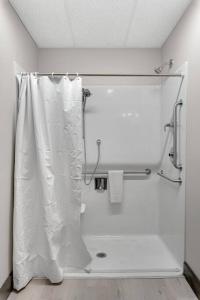 a bathroom with a shower with a white shower curtain at Barnwood Suite - Main Street Lodge in Berlin in Berlin