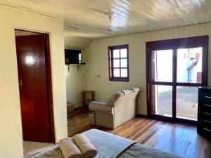 a room with a bed and a couch and a window at Central Chalés in Cambara do Sul