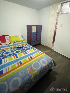 a bedroom with a bed with a colorful comforter at Hospedaje Holcay in Bogotá