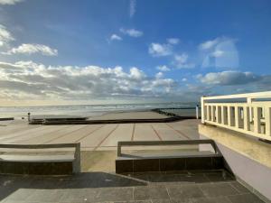 een uitzicht op het strand met banken op een gebouw bij Les Lutins - sur la plage in Wimereux