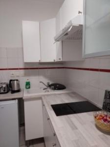 una cocina con armarios blancos y fregadero en Studio en résidence parking couvert gratuit, en Peyraud