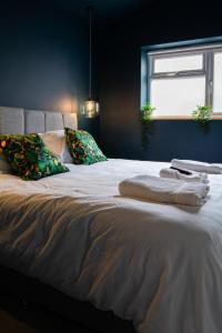 - un lit avec des draps et des oreillers blancs ainsi qu'une fenêtre dans l'établissement Sleeps 16 with style and space- and a hot tub!, à Newquay