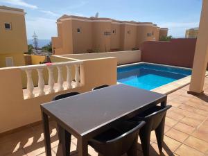 una mesa y sillas en un balcón con piscina en Casa Mariben, Vacation Rental home Vv 3 Bedrooms private pool with sea views, en Callao Salvaje