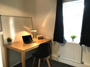 un escritorio con ordenador portátil junto a una ventana en Modern 3-bed house with parking Bamber Bridge, Preston, en Bamber Bridge