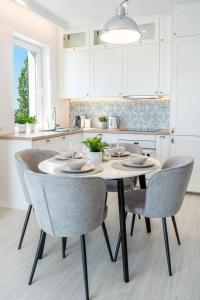 eine weiße Küche mit einem Tisch und Stühlen in der Unterkunft Belle View Apartment in Iława