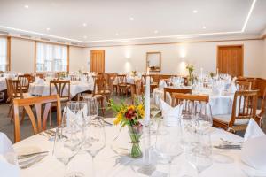 une salle de banquet avec des tables, des chaises et des fleurs dans un vase dans l'établissement Landgasthof Wartegg, à Wigoltingen