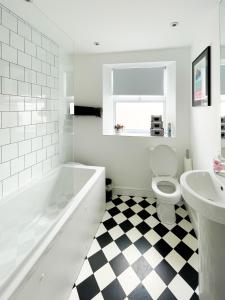 a bathroom with a tub and a toilet and a sink at Sleeps 16 with style and space- and a hot tub! in Newquay