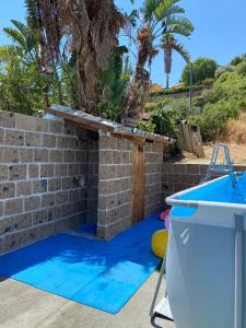 a swimming pool with a brick wall next to a blue swimming pool at Baglio Zio Ciccio in Altavilla Milicia