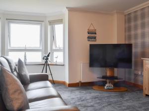 a living room with a couch and a flat screen tv at Aurora in Lossiemouth