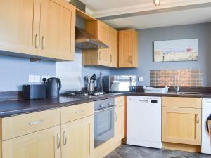 a kitchen with wooden cabinets and a white dishwasher at Aurora in Lossiemouth