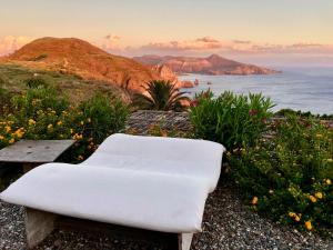 a white chair sitting on top of a hill with the ocean at Case Quattrocchi - Giardino e Terrazzi con vista Panoramica sul Mare, Etna e Vulcano in Lipari