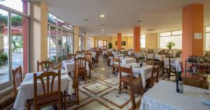 un restaurante con mesas y sillas blancas y ventanas en Hotel Andalucia, en Lanjarón