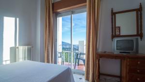 a bedroom with a bed and a television and a balcony at Hotel Andalucia in Lanjarón