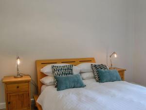 a bedroom with a white bed with two pillows at Lime Tree Cottage in Drumpark