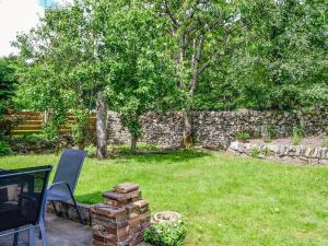 einen Garten mit einem Tisch, Stühlen und einer Steinmauer in der Unterkunft Lime Tree Cottage in Drumpark