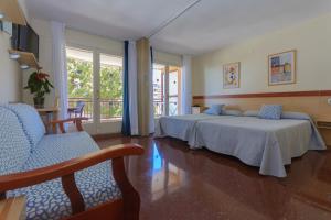 a bedroom with two beds and chairs and a balcony at Beach Family Apartments in Salou