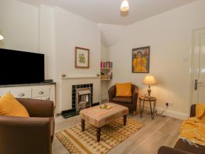 a living room with a fireplace and a tv at Primrose Cottage in Cheltenham