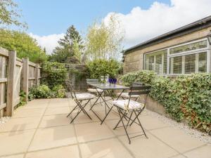 un patio con mesa y sillas en un jardín en Primrose Cottage en Cheltenham