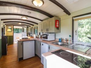 une cuisine avec des placards blancs et une grande fenêtre dans l'établissement The Brake Wagon at High Barn Heritage, à Halstead