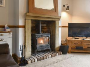 a fireplace in a living room with a stove at Waterside Cottage in Winewall