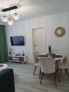 un soggiorno con tavolo, sedie e TV di Apartament AMA Sibiu a Sibiu