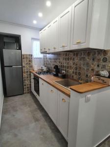 La cuisine est équipée de placards blancs et d'un réfrigérateur en acier inoxydable. dans l'établissement Apartament AMA Sibiu, à Sibiu