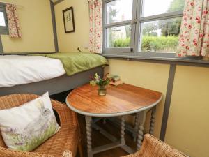 ブレコンにあるBrown Hare Shepherds Hutのテーブルとベッド、窓が備わる客室です。