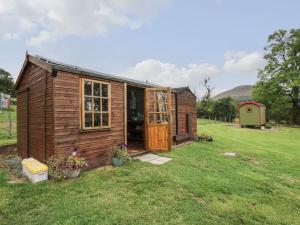 um pequeno barracão de madeira num campo de relva em Sweet Briar Shepherds Hut em Brecon
