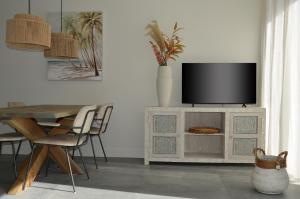 a living room with a tv on top of a cabinet at Olive Beach, luxury beachhouse 150 m from the beach in Noordwijk aan Zee
