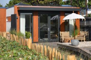 a house with an umbrella and chairs in front of it at Have a nice stay! - Olive Beach, luxury beachhouse 150 m from the beach in Noordwijk aan Zee