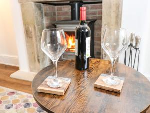 una bottiglia di vino seduta su un tavolo con due bicchieri da vino di April Cottage a Keighley