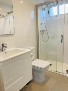 a white bathroom with a toilet and a shower at Sunnybeach Apartment mit direktem Strandzugang in Denia
