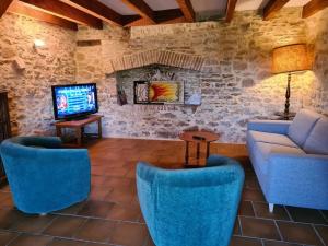 sala de estar con sillas azules, sofá y TV en Maison chaleureuse près de Rocamadour, en Alvignac