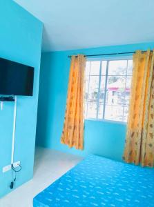 a blue room with a bed and a window at Daisy Aircon Room 1 with Private Toilet and Bath in Bacolod