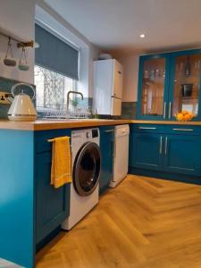 a kitchen with blue cabinets and a washing machine at Sea View Cottage in Dorset, Portland in Portland