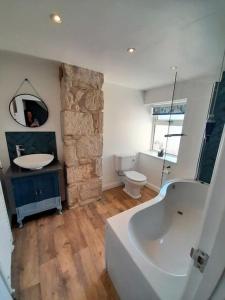 ein Badezimmer mit einer Badewanne, einem Waschbecken und einem WC in der Unterkunft Sea View Cottage in Dorset, Portland in Portland