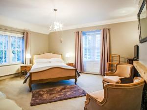 a bedroom with a bed and a chair and windows at Blashford Manor Farm House in Ellingham