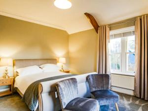 a bedroom with a large bed and two chairs at Blashford Manor Farm House in Ellingham