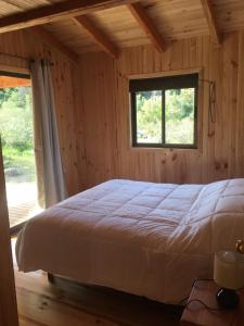 a bedroom with a bed and a window at Los Quenes River Lodge in Los Queñes