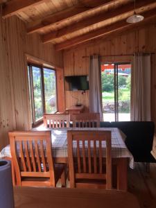 a dining room with a table and chairs and windows at Los Quenes River Lodge in Los Queñes