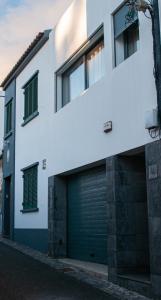 a white building with a green garage door at Sailorman and Friends in Ponta Delgada