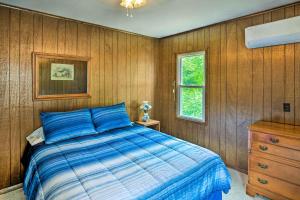 1 dormitorio con cama azul y pared de madera en Secluded Getaway Less Than 10 Mi to Saratoga Springs!, en South Corinth