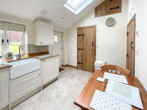 a kitchen with white cabinets and a wooden table at The Old Pump House - Uk34451 in Child Okeford