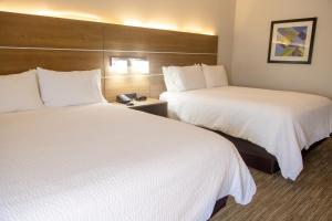 two beds in a hotel room with white sheets at Holiday Inn Express Marshfield - Springfield Area by IHG in Marshfield