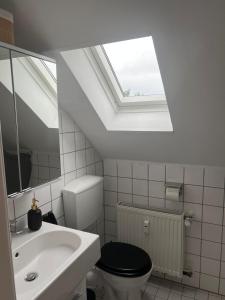 łazienka z toaletą, umywalką i oknem dachowym w obiekcie Ferienwohnung OG Zentrum Neuss w mieście Neuss