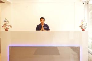 Un homme se tient derrière un comptoir blanc avec ses mains dans l'établissement Gateway Inn, à Bangalore