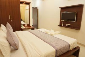 ein Schlafzimmer mit einem großen Bett und einem TV an der Wand in der Unterkunft Gateway Inn in Bangalore
