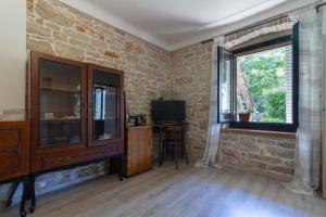 ein Wohnzimmer mit einer Ziegelwand und einem Fenster in der Unterkunft Holiday stone house in Bale