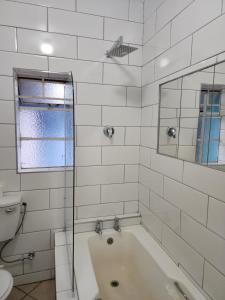 a white bathroom with a tub and a toilet at Hasate Guest House ,4 st james street Oakdale Belliville Cape Town South Africa in Cape Town
